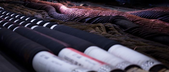Close-up image of multiple large water-cooled cables in storage, emphasizing their thickness and coiled structure.